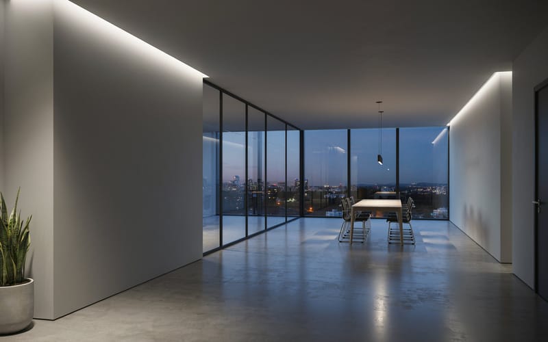A minimalist modern office at dusk with a glass partition and a city skyline through the windows