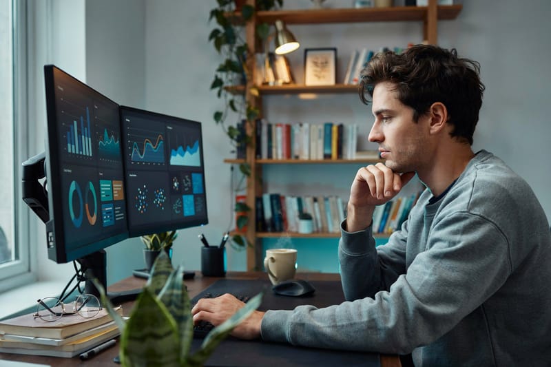 An analyst reviewing data dashboards on dual monitors