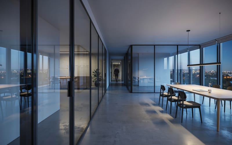 A modern office corridor at dusk with a figure walking toward the city view