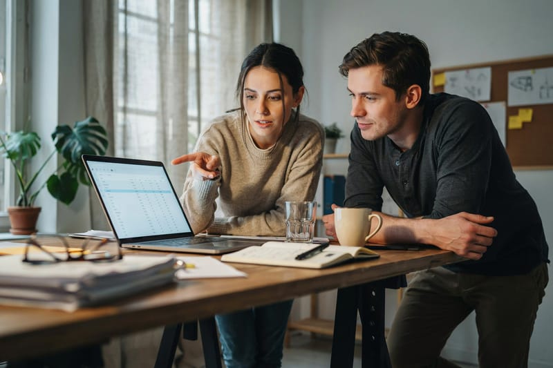 Two colleagues working together over a laptop