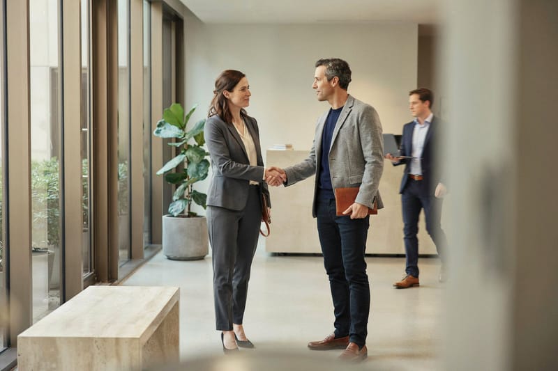 Two professionals shaking hands in a bright office