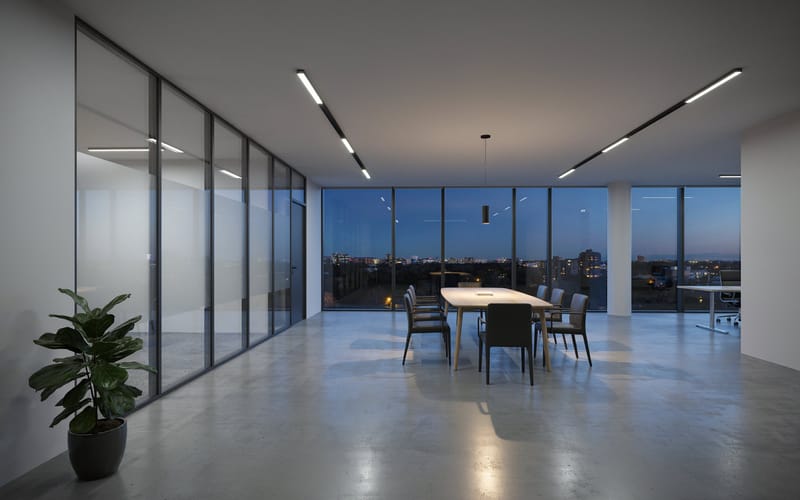 A quiet modern office at night with a long table and a city view through the windows