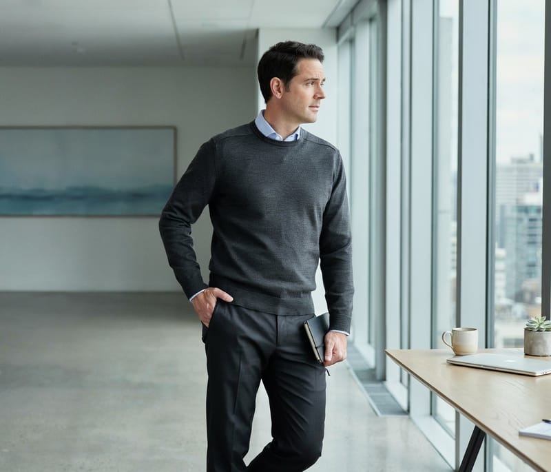 A technology leader standing by a window with a tablet, looking out over the city